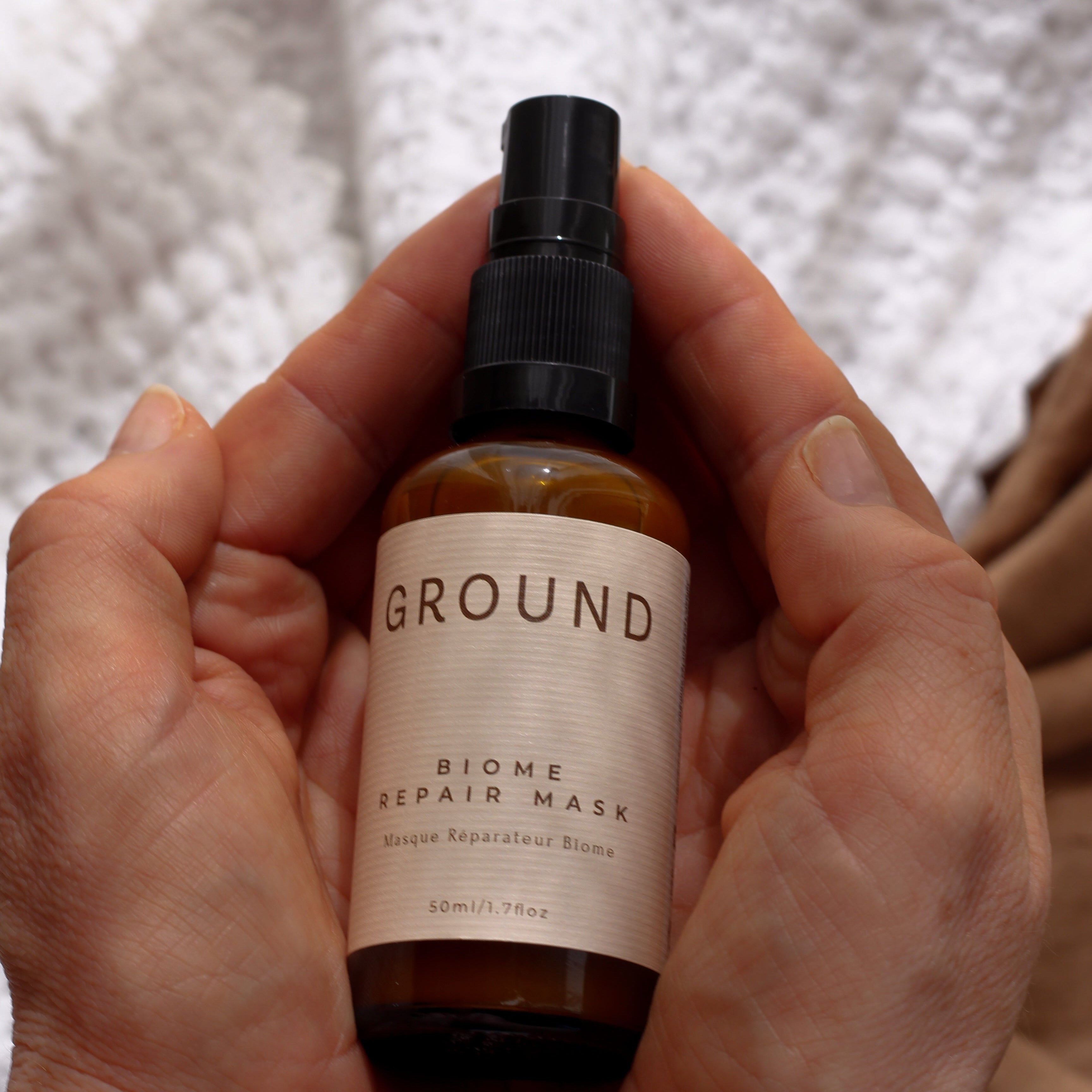 Hands holding a bottle of Biome Repair Mask