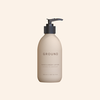 Image of a beige lotion bottle with dark grey pump lid on a beige background. On the bottle in light brown it says GROUND Hand & Body Lotion - lavender and cedarwood. Quantity 300ml.