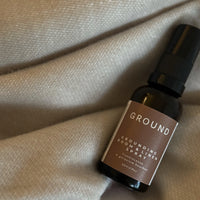 Photograph of a small brown glass spray bottle of grounding room and linen spray containing frankincense and geranium bourbon.
