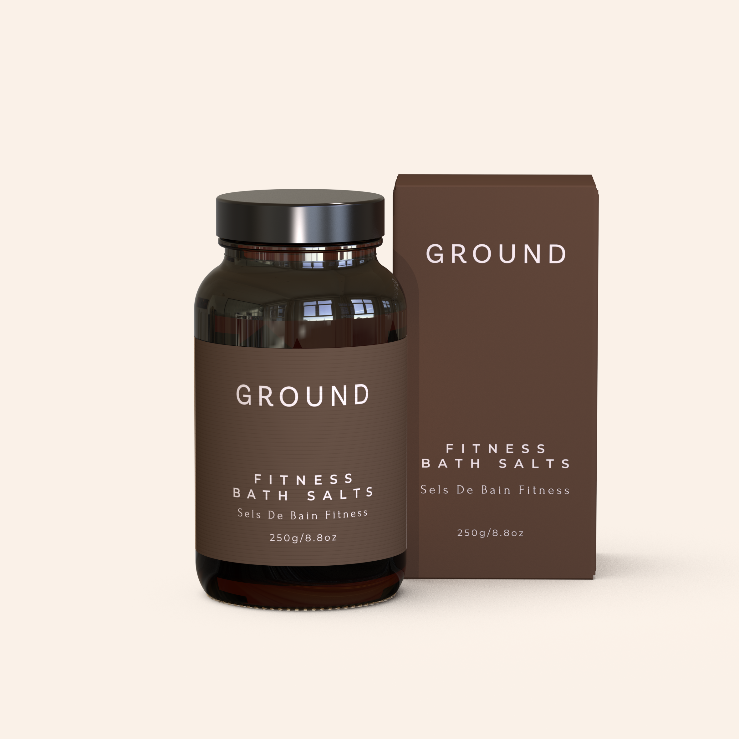 A mock up image showing a bottle and packaging of 'GROUND' Fitness Bath Salts on a light beige background. The bottle is made from glass and has a brown label with white writing describing the product as fitness bath salts, sels de bain fitness, 250g. It sits beside an image of a dark brown cardboard box as its packaging with the same detials written on it.