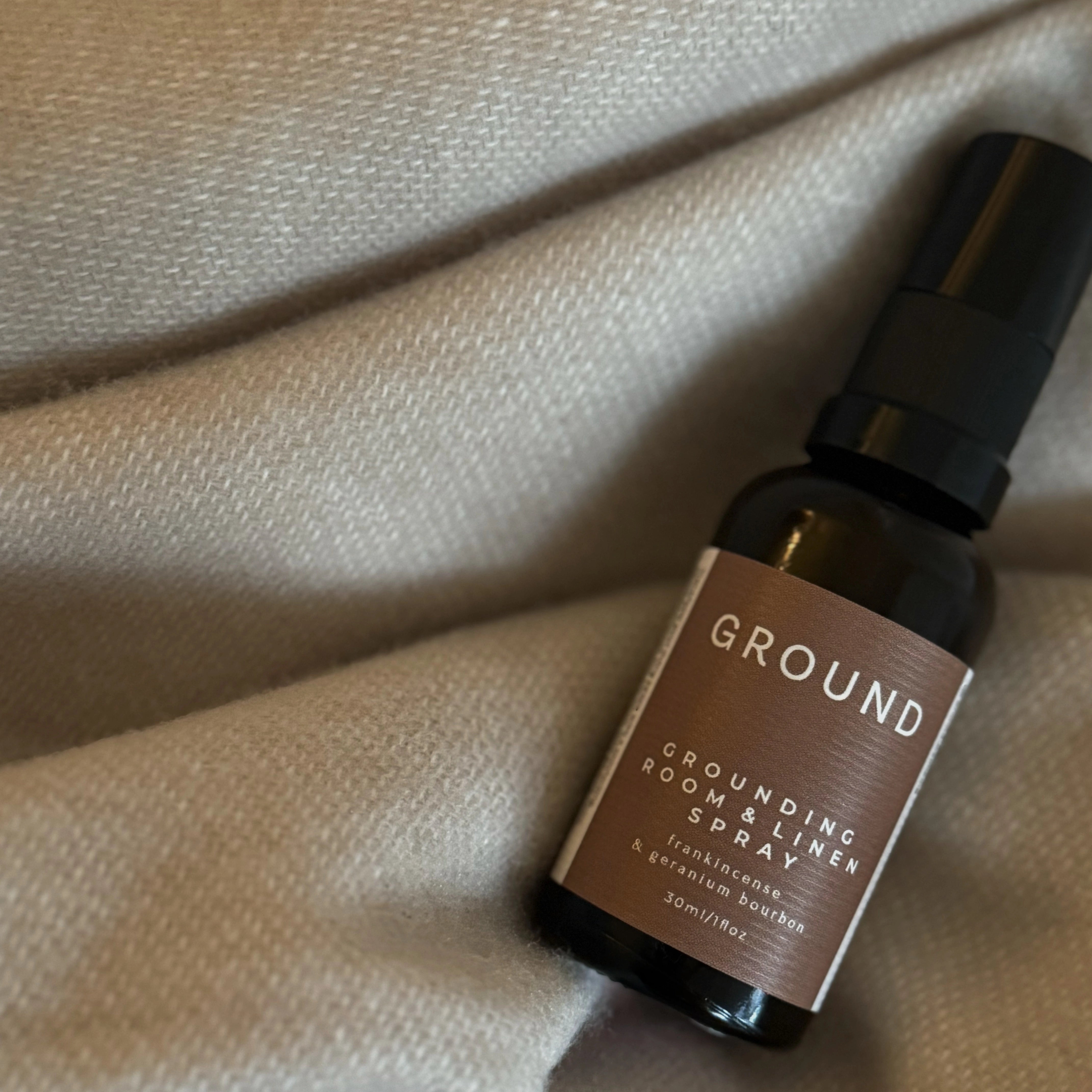 Photograph of a small brown glass spray bottle of grounding room and linen spray containing frankincense and geranium bourbon.