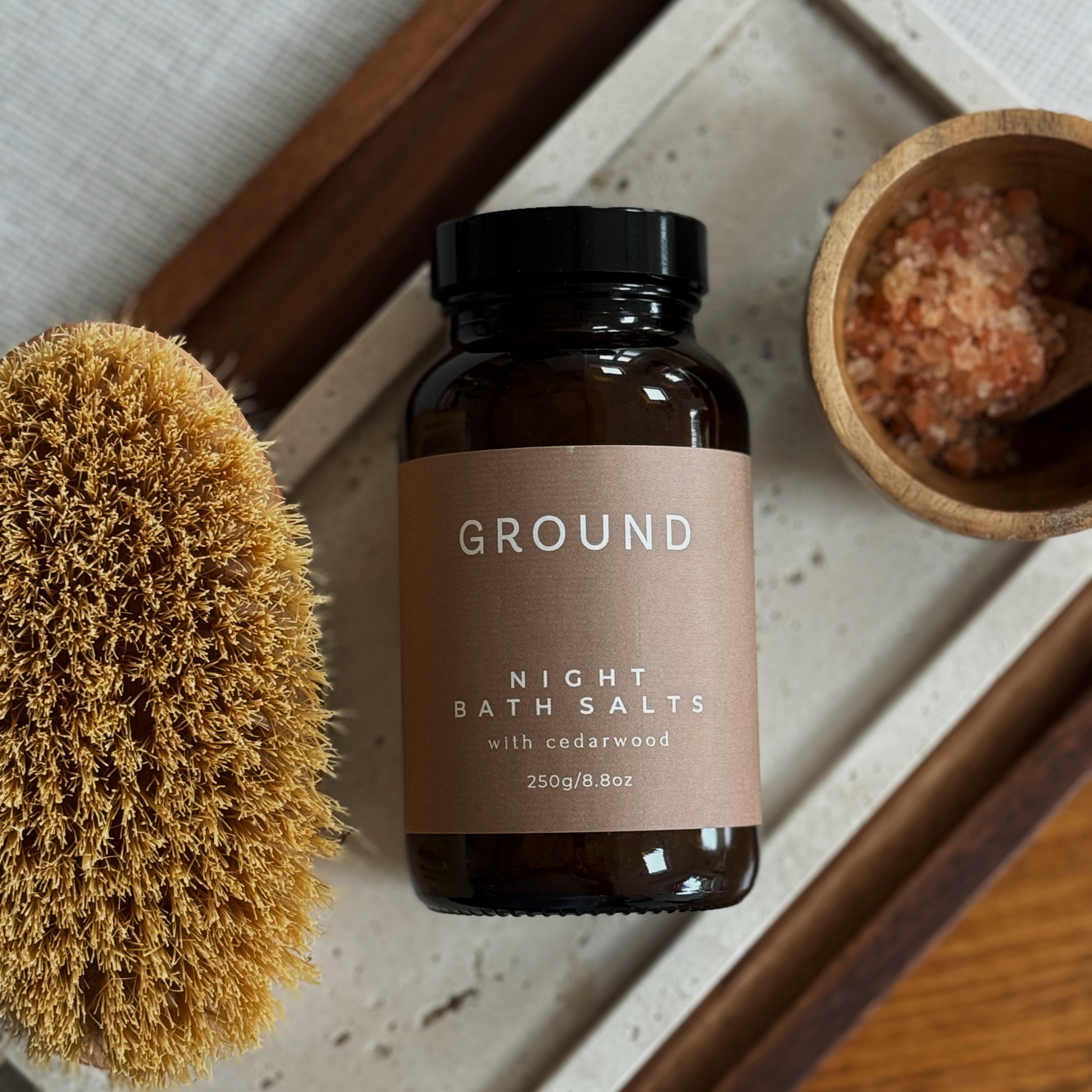 Jar of GROUND Night Bath salts on a tray with salts in a bowl and body brush